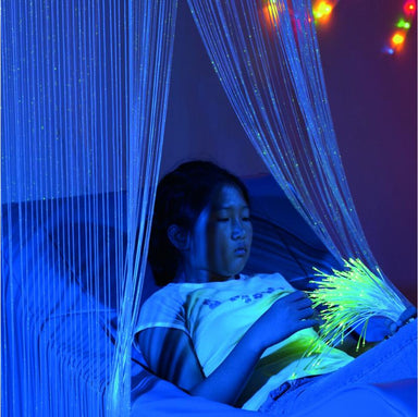 Girl lying under TFH Fiber Optic Waterfall in dark sensory room