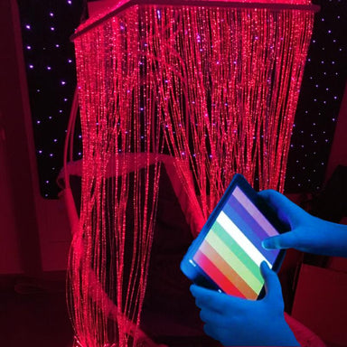 Person holding a tablet with a colorful screen in front of a TFH Genie Controlled Fiber Optic Waterfall