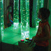 child interacting with TFH Interactive Bubble Tubes in sensory room with green lighting