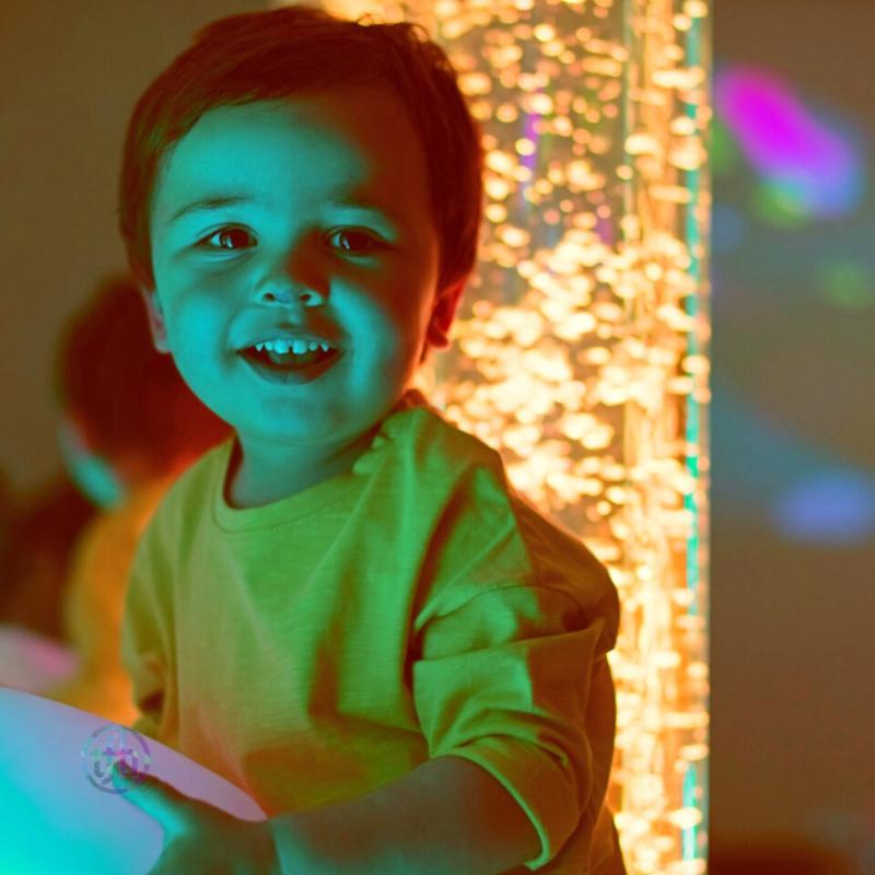 Small boy laughing in front of TFH Interactive Bubble Tubes with yellow lights