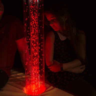 Two people sitting next to a TFH Interactive Hurricane Tube with red light in sensory room
