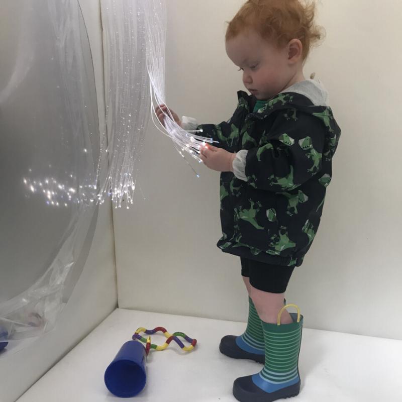 Child playing with the Fiber Optic Spray inside the TFH Portable Sensory Den 