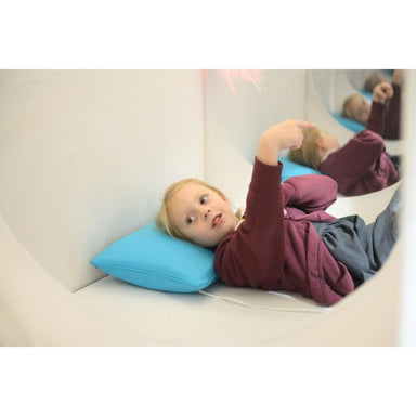 Child lying on a blue pillow inside of a TFH Portable Sensory Den