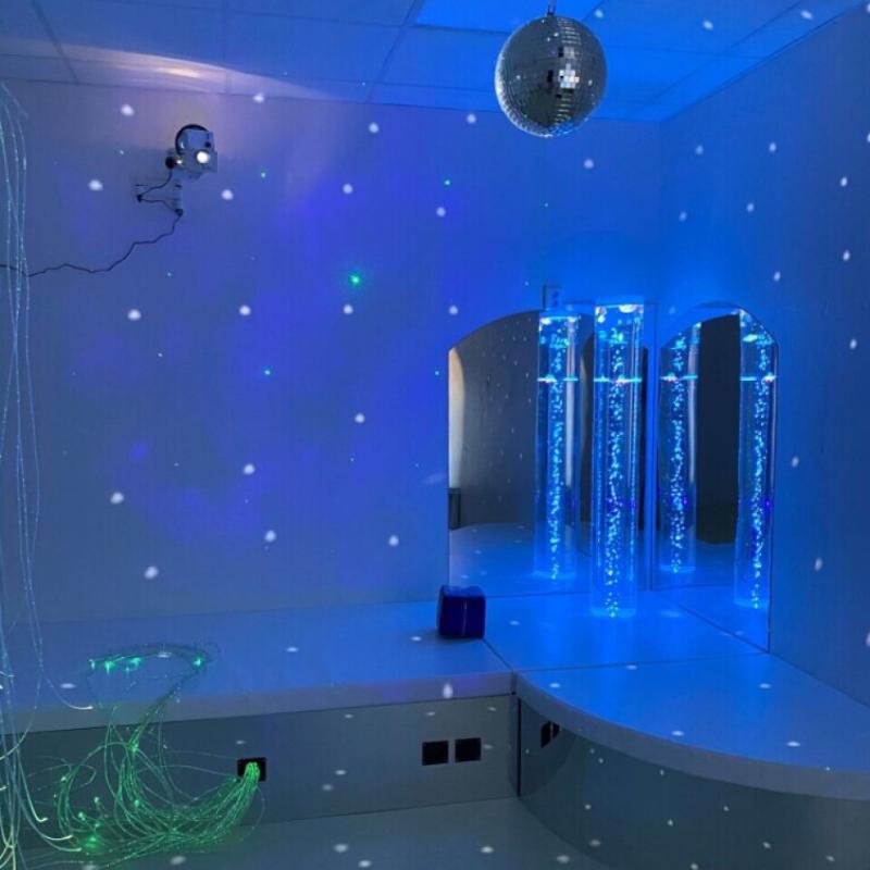 TFH Quadrant Podium Bench in a sensory room with bubble tubes, fiber optic sprays and a disco ball
