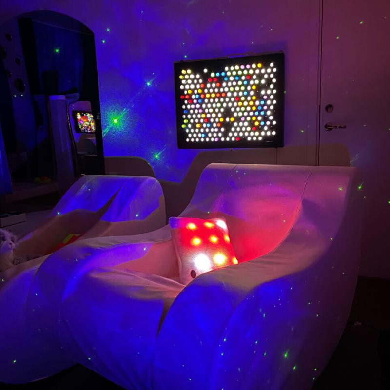 TFH Rod Wall Light Panel hanging on the wall of a sensory room with 2 loungers