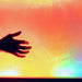 Silhouette of a hand reaching towards a colorful, gradient TFH Sound & Light Panel