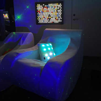 Two TFH Therapy Chairs in a dark sensory room  with light panels in the background