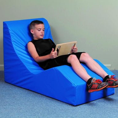 Boy relaxing in a TFH Vibroacustic Relaxer Chair with a tablet in his hands
