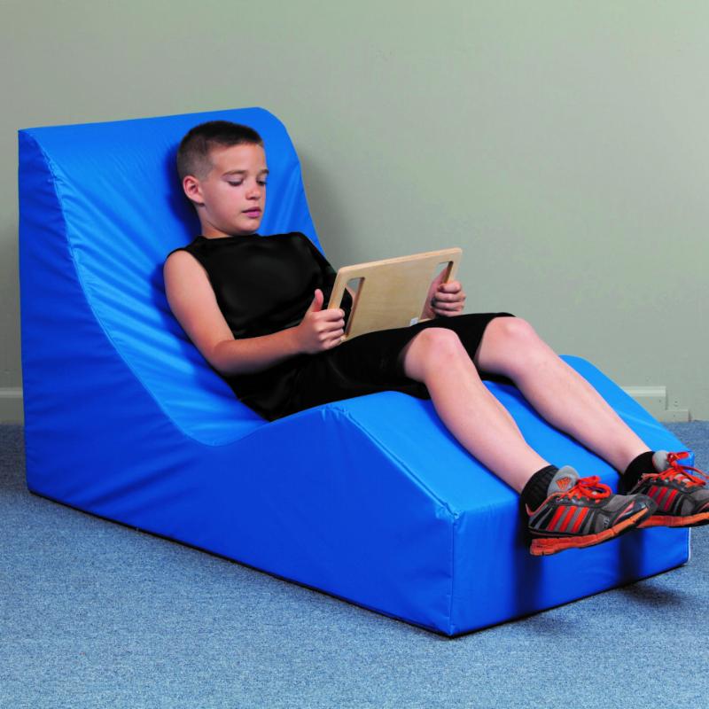 Boy relaxing in a TFH Vibroacustic Relaxer Chair with a tablet in his hands