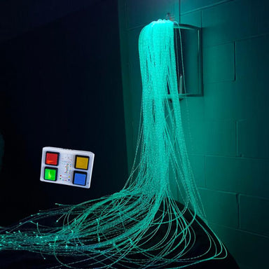 TFH Wireless Fiber Optic Wall Sconce with Tails with controller in blue lighting in dark sensory room